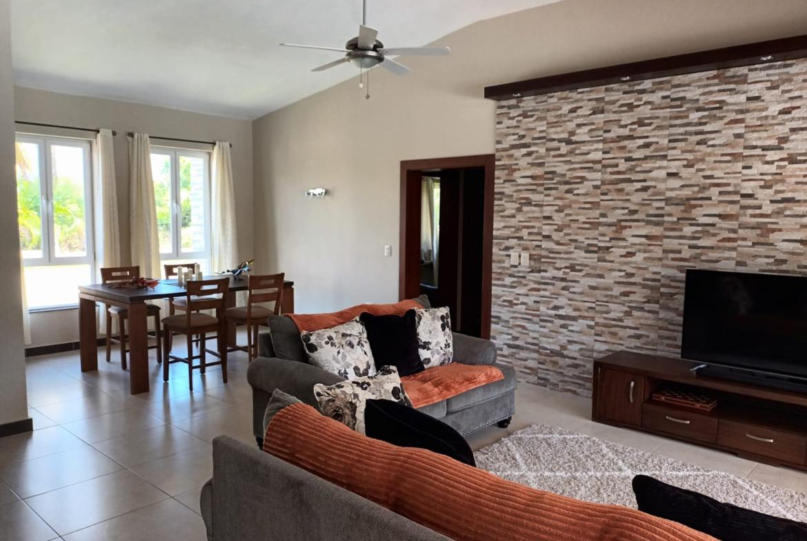 Modern living room with sectional sofa, textured wall, and dining area