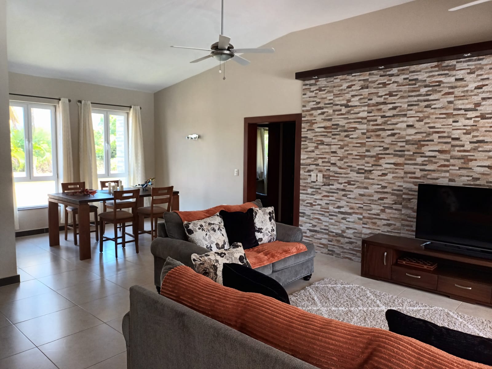 Modern living room with sectional sofa, textured wall, and dining area