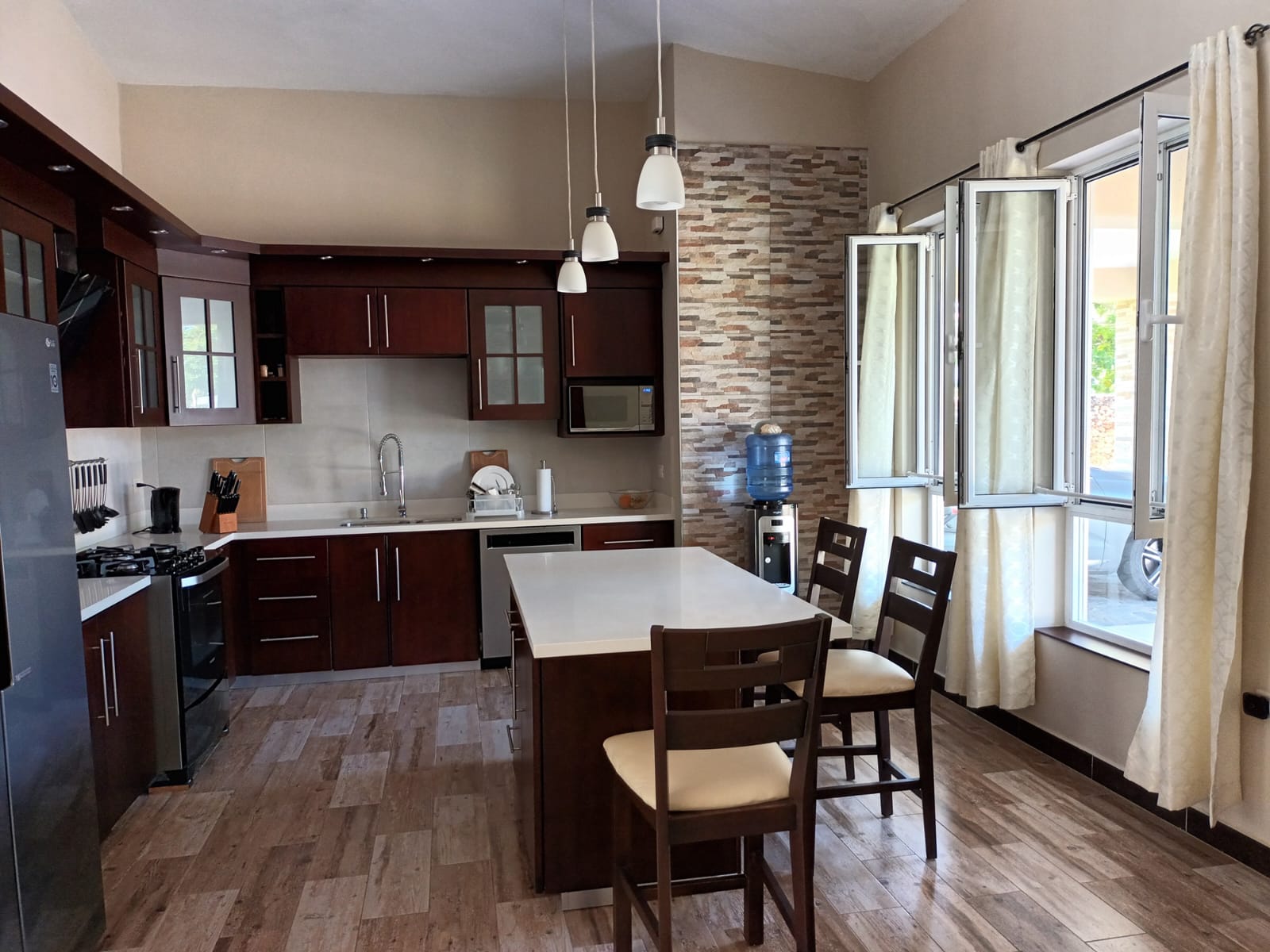 Modern kitchen with dark wood cabinets, island, and large windows