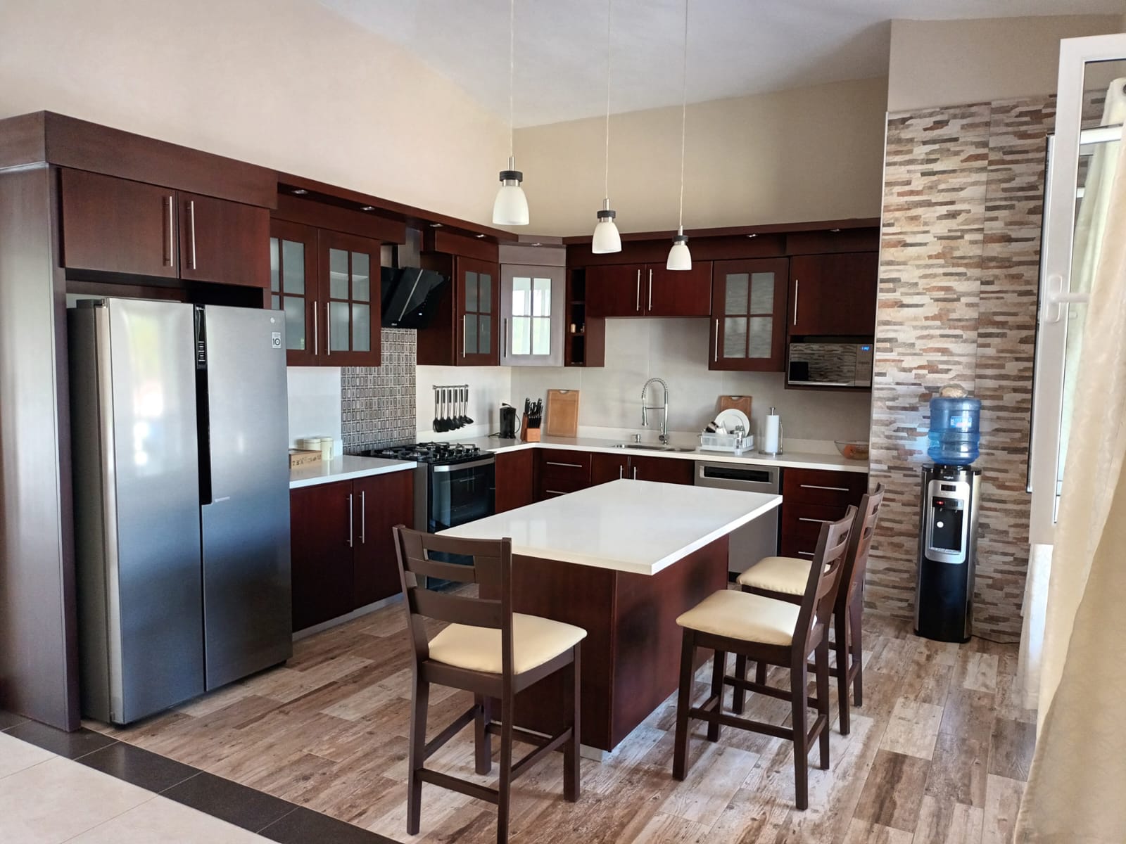 Modern kitchen with dark wood cabinets, island, and stainless steel appliances.