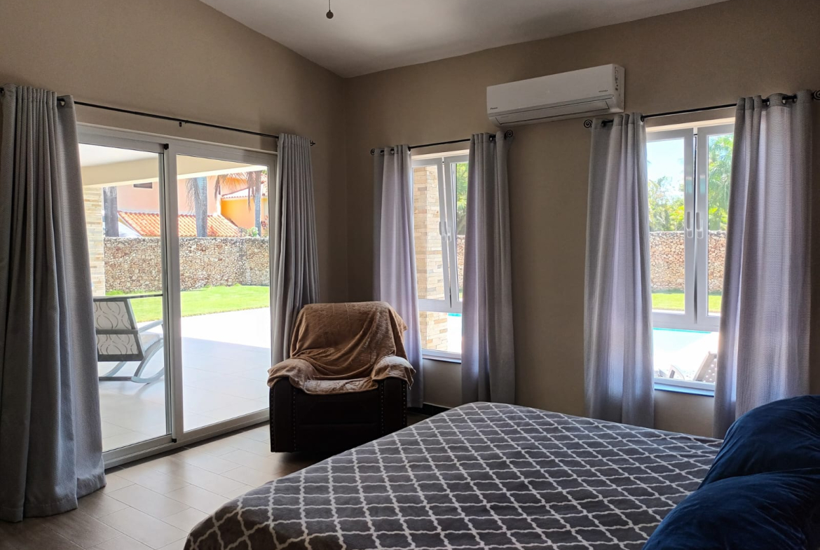 Comfortable bedroom with large windows, a recliner, and a bed with patterned bedding.