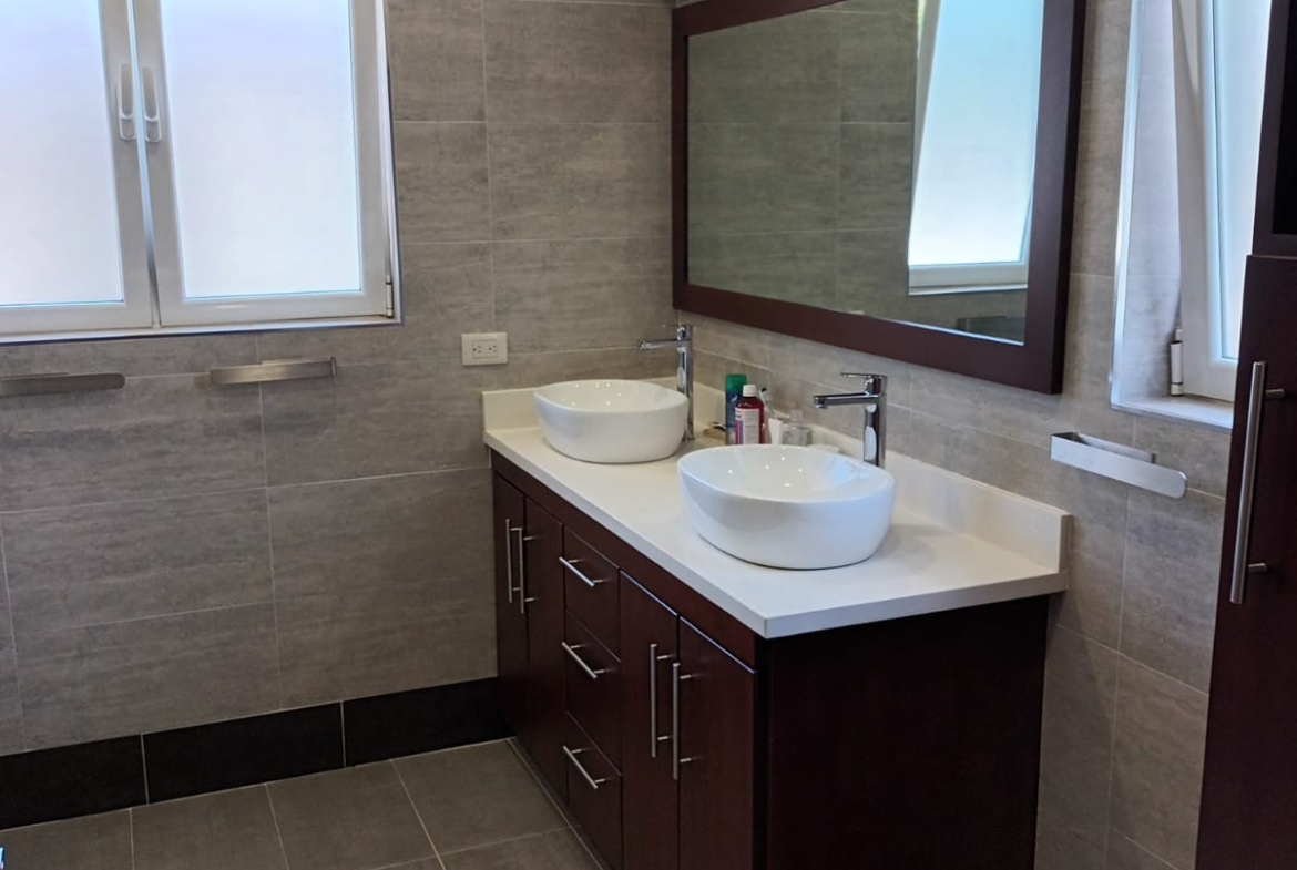 Modern bathroom with a double vanity, vessel sinks, and tiled walls.