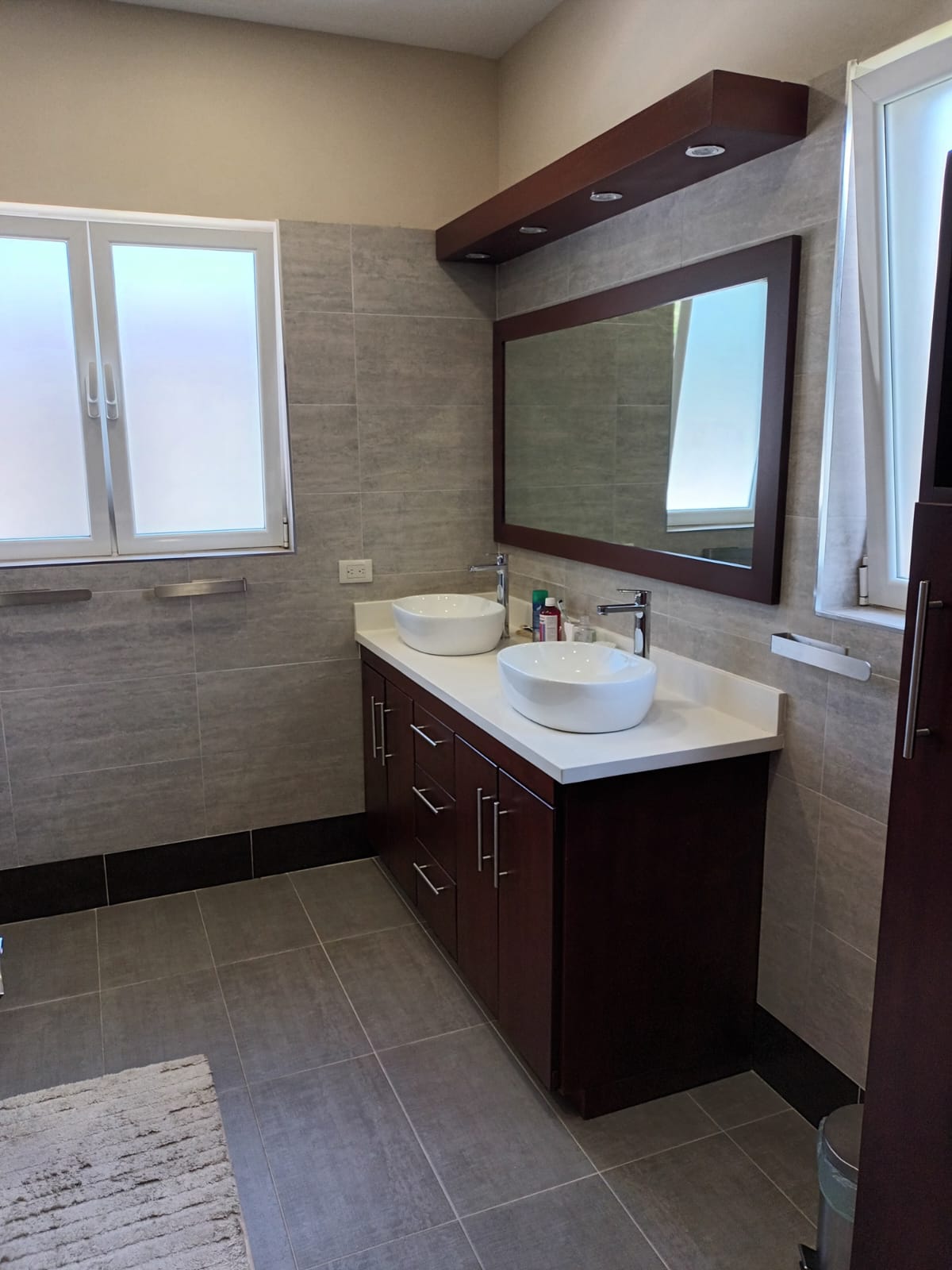 Modern bathroom with a double vanity, vessel sinks, and tiled walls.