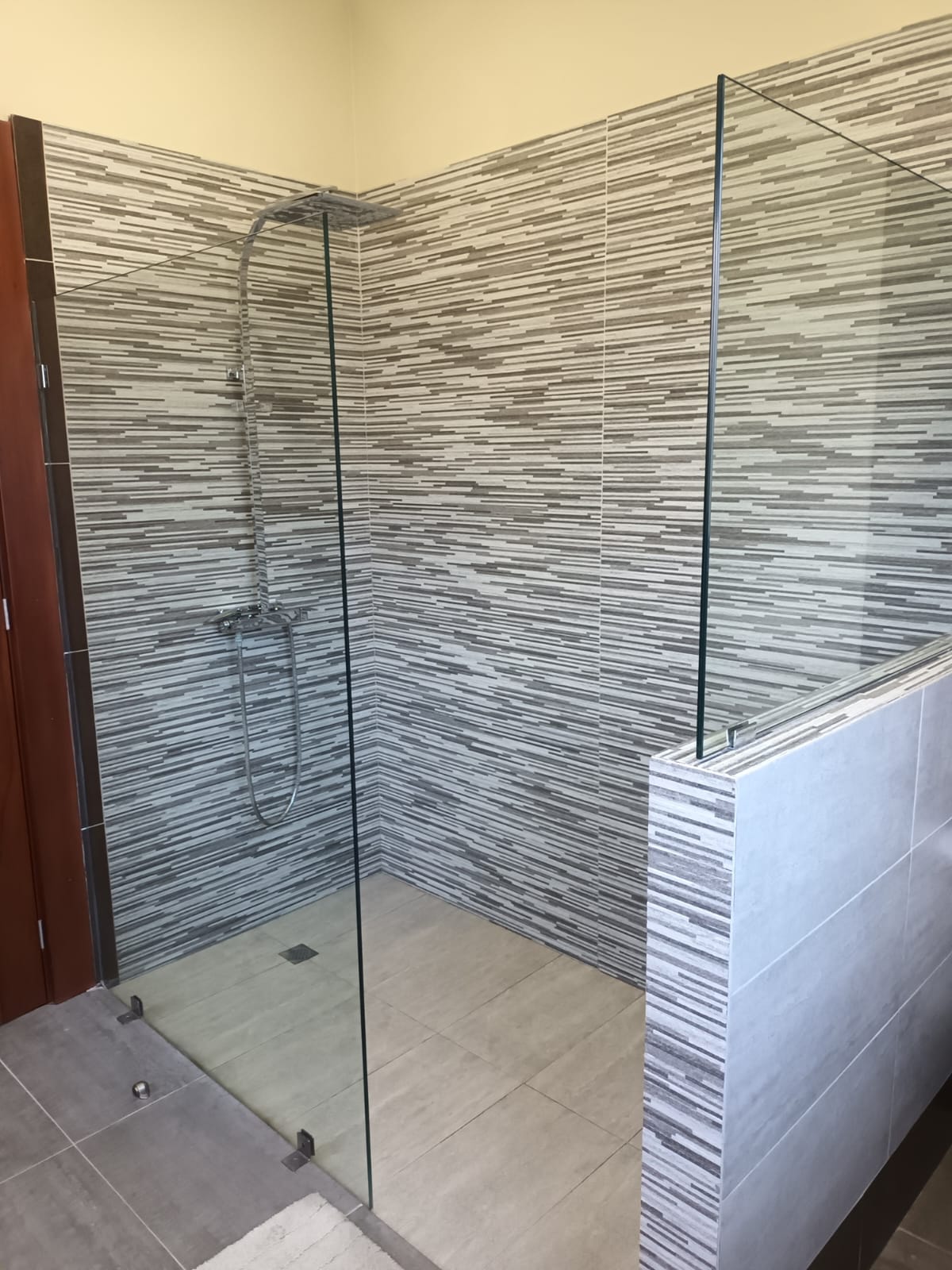 Modern walk-in shower with glass enclosure and striped tile