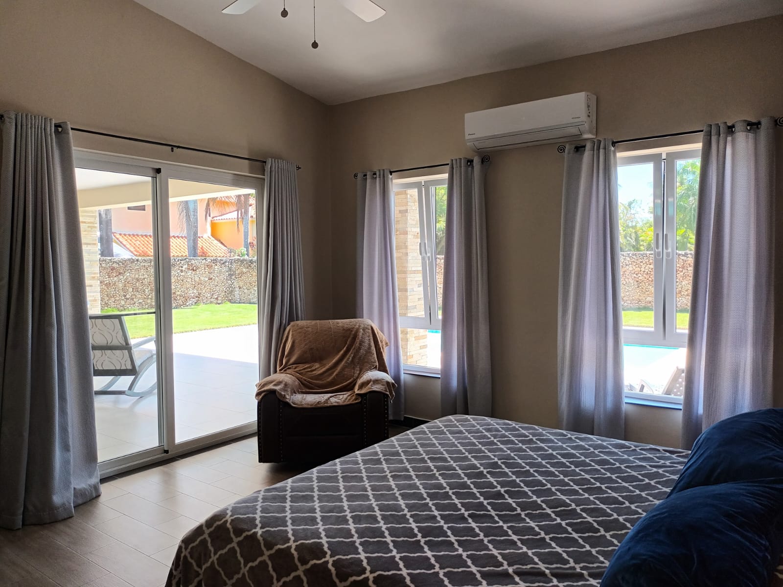 Comfortable bedroom with large windows, a recliner, and a bed with patterned bedding.