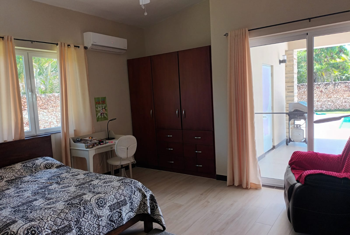 Bedroom with a large wardrobe, desk, bed, and patio doors leading to a pool area.
