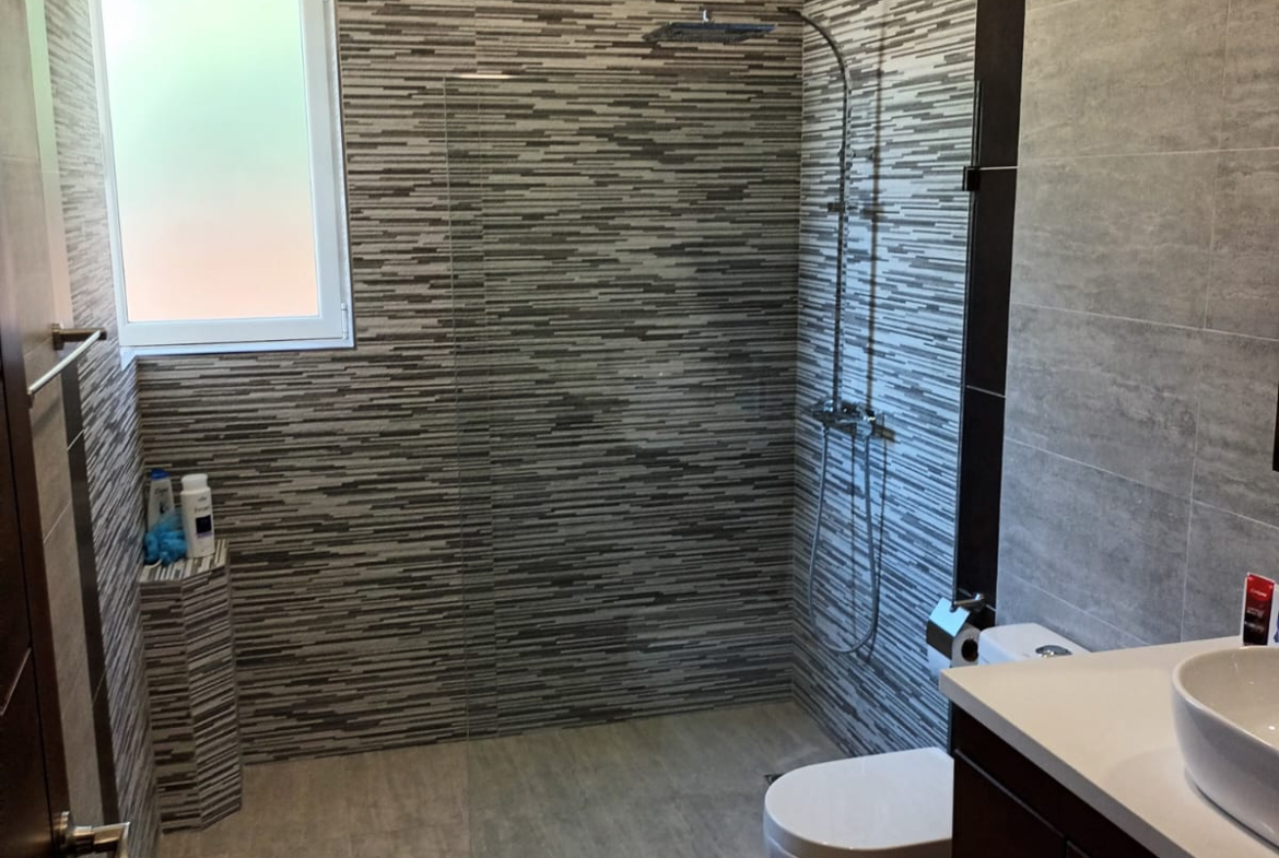 Modern bathroom with tiled shower, vanity, and toilet
