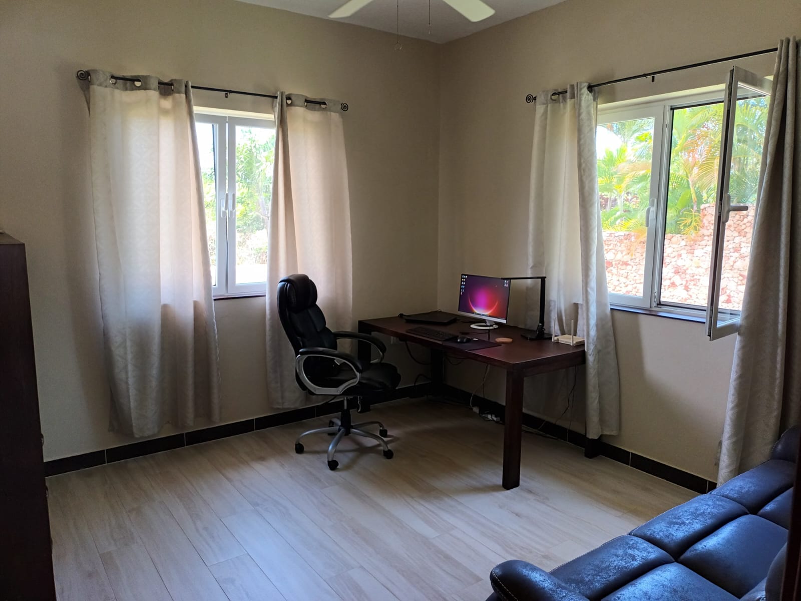Home office with desk, computer, and ergonomic chair near window