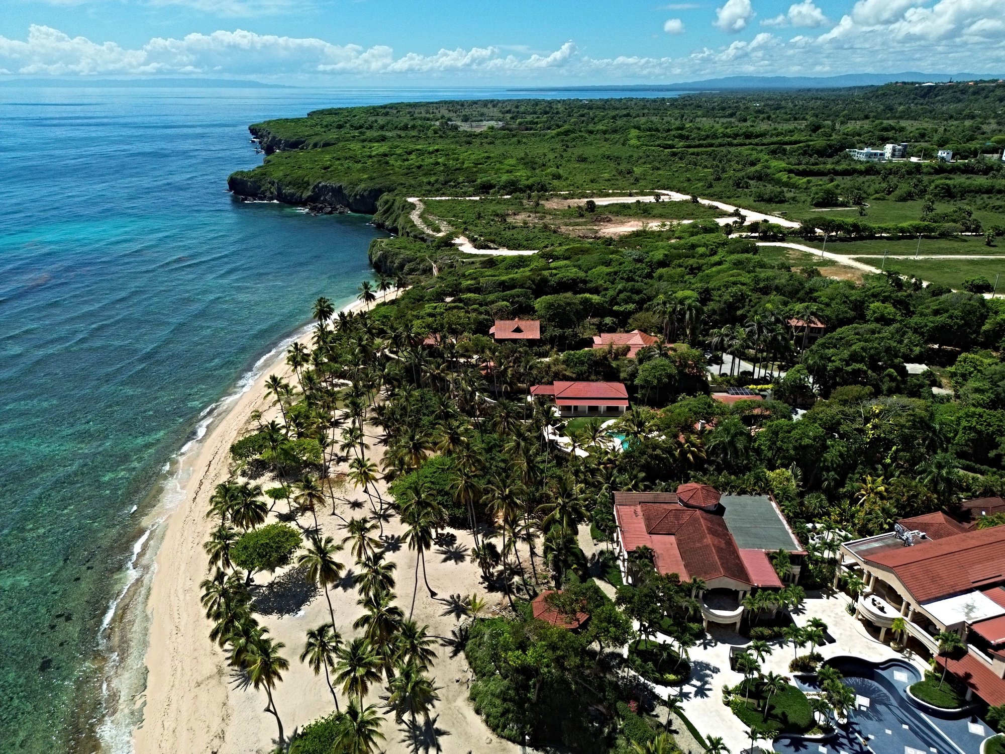 Aerial view of a tropical resort with palm trees, beach, and ocean