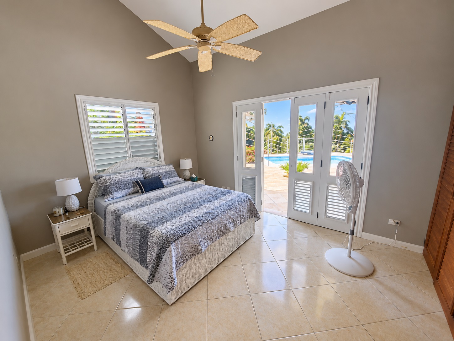 Bedroom with king-size bed, ceiling fan, and patio doors opening to a pool.