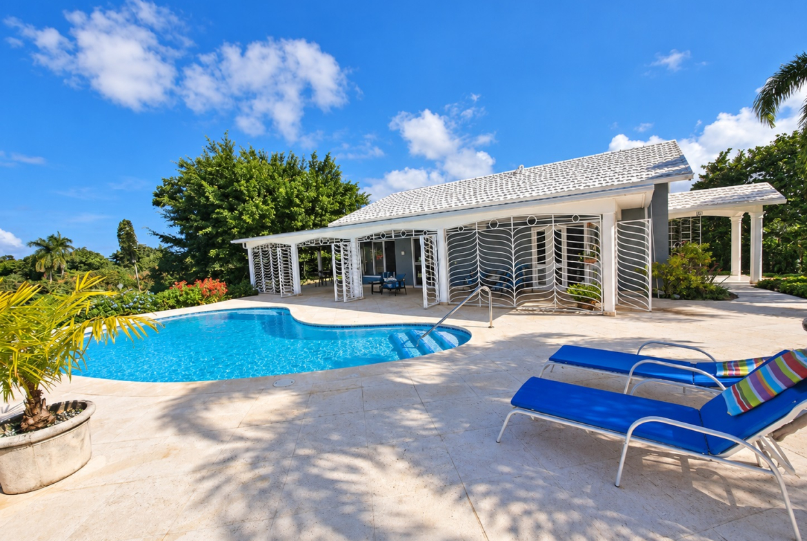 Luxury villa with swimming pool and lounge chairs in sunny Jamaica