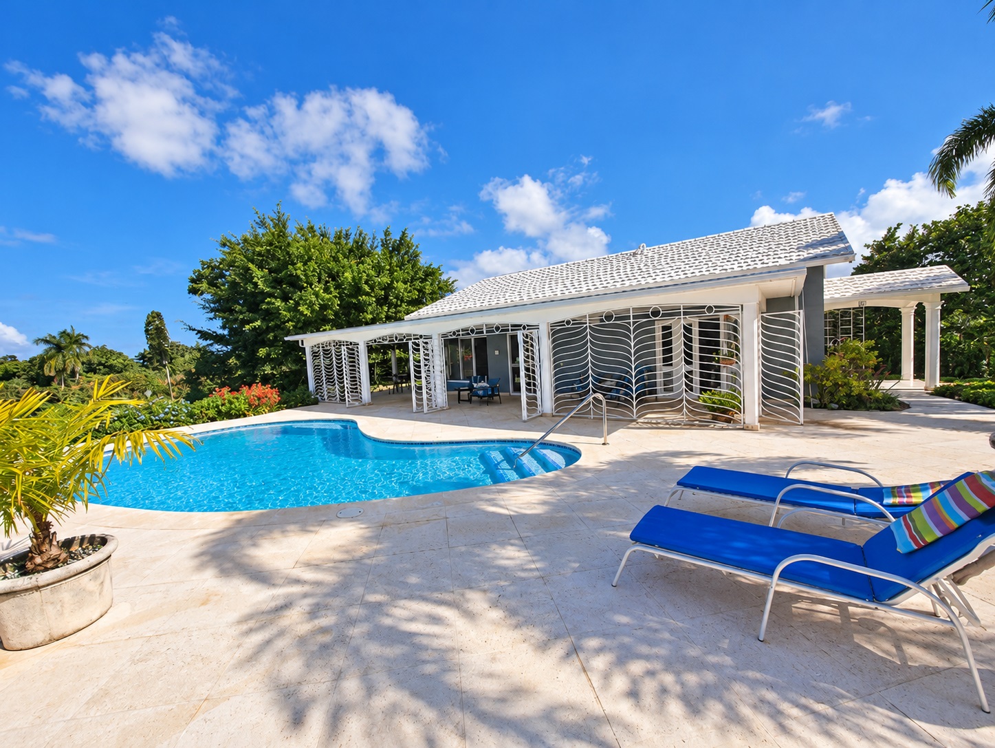 Luxury villa with swimming pool and lounge chairs in sunny Jamaica