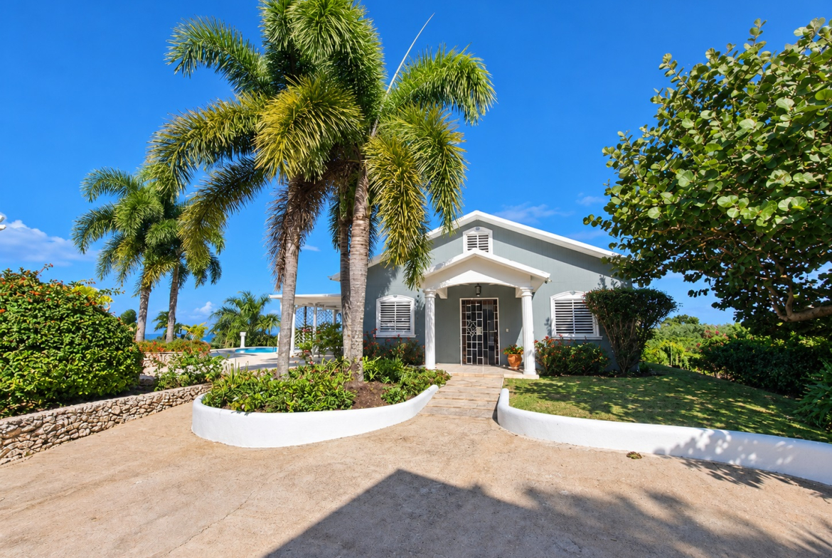 Tropical home with palm trees and swimming pool under a clear blue sky.