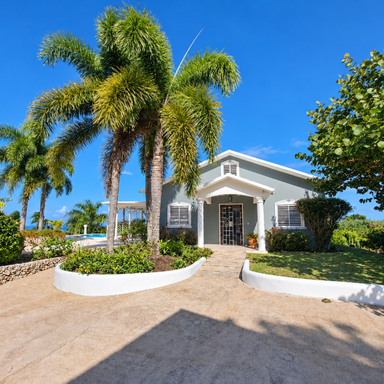 Tropical home with palm trees and swimming pool under a clear blue sky.