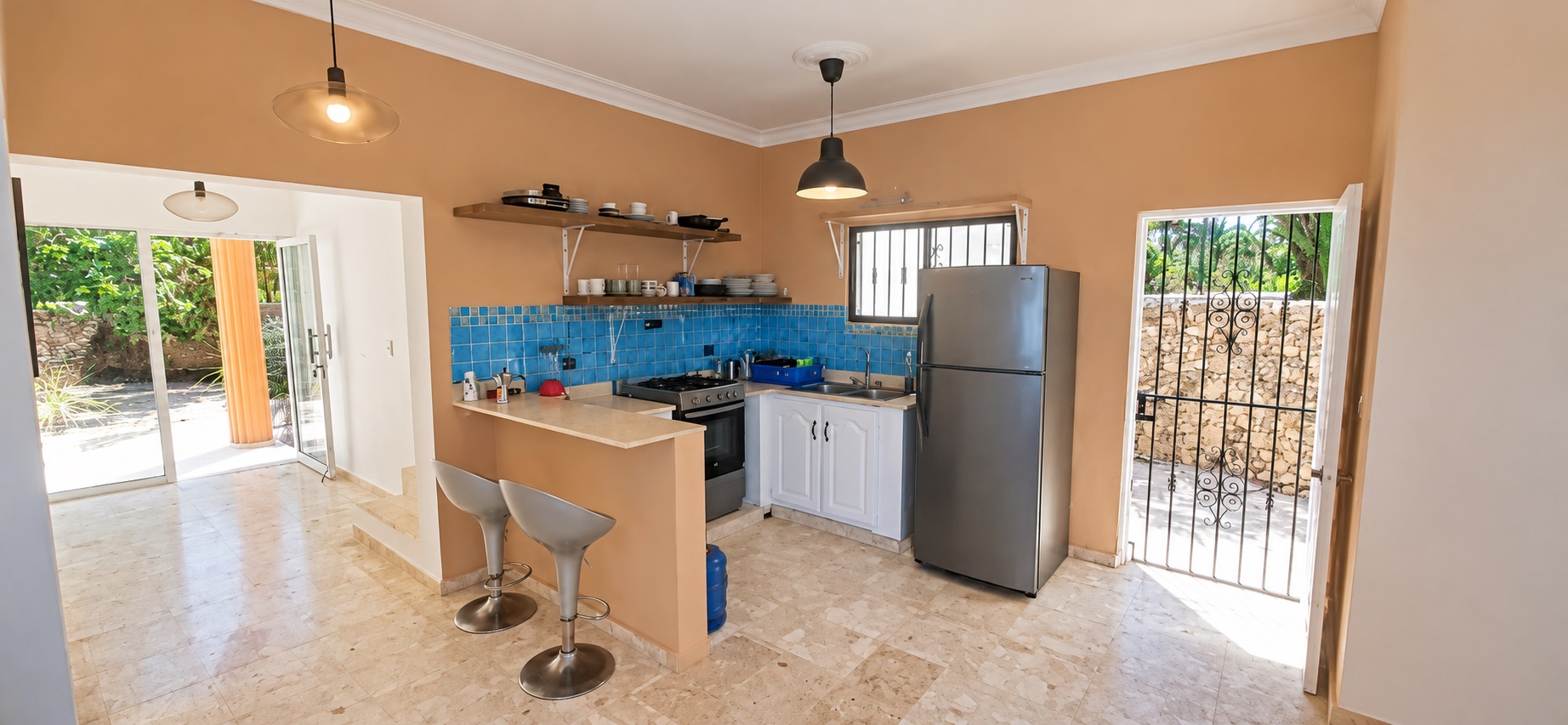 Modern kitchen with stainless steel appliances, breakfast bar, and orange walls.