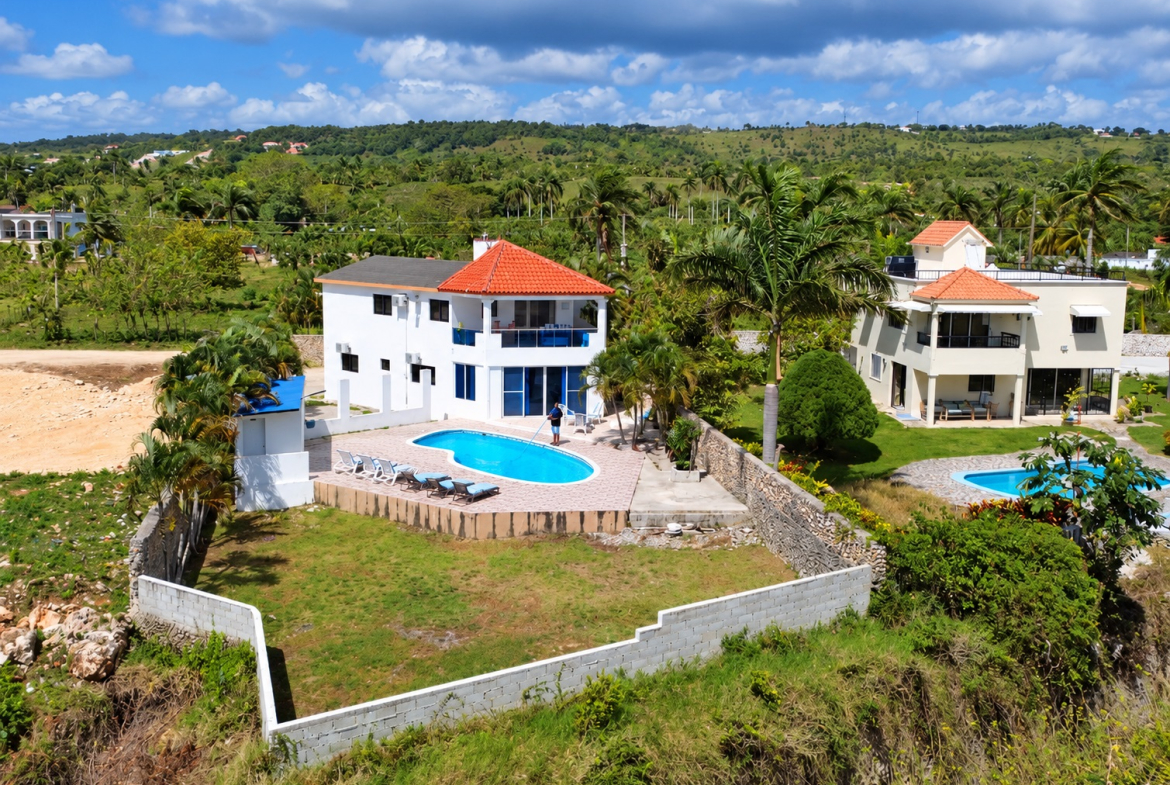 Luxury villa with pool, palm trees, and lush green landscape