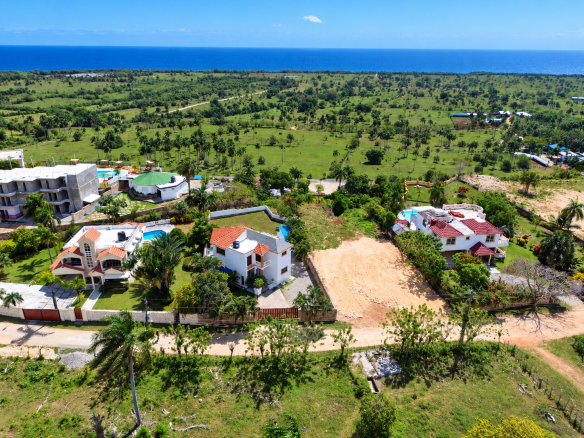Aerial view of luxury villas with pools and ocean backdrop in a tropical landscape
