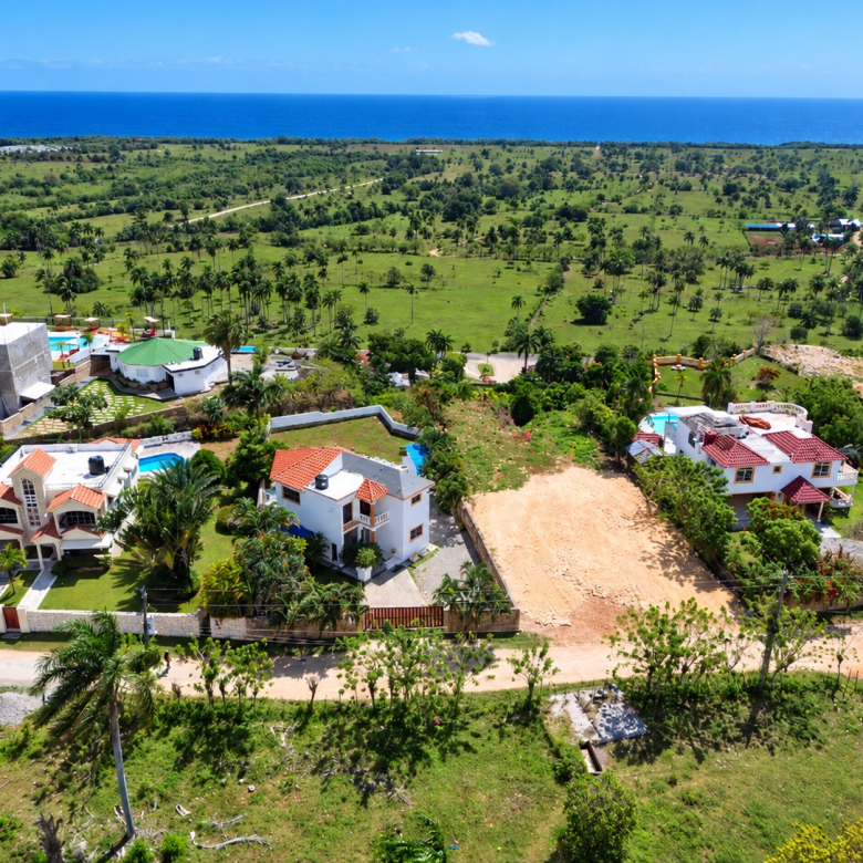 Aerial view of luxury villas with pools and ocean backdrop in a tropical landscape