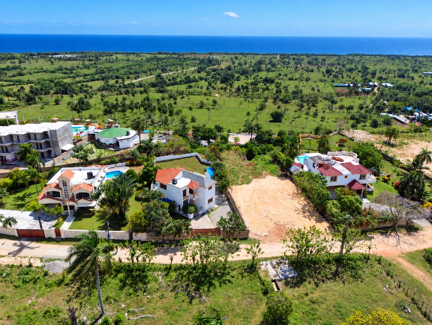 Aerial view of luxury villas with pools and ocean backdrop in a tropical landscape